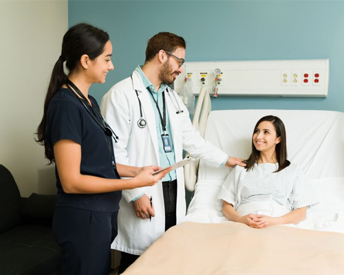 a woman in a hospital bed talking to a doctor