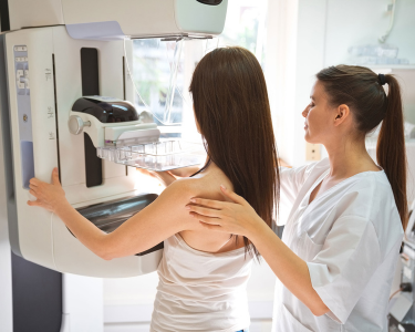 A medical technician assisting a patient with a mammogram.